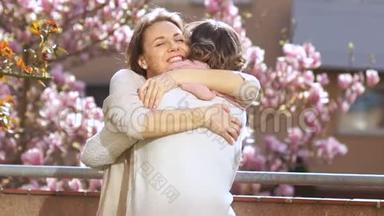 母女在母亲节`互相祝贺.. 女儿抱着一位年迈的母亲，背景是
